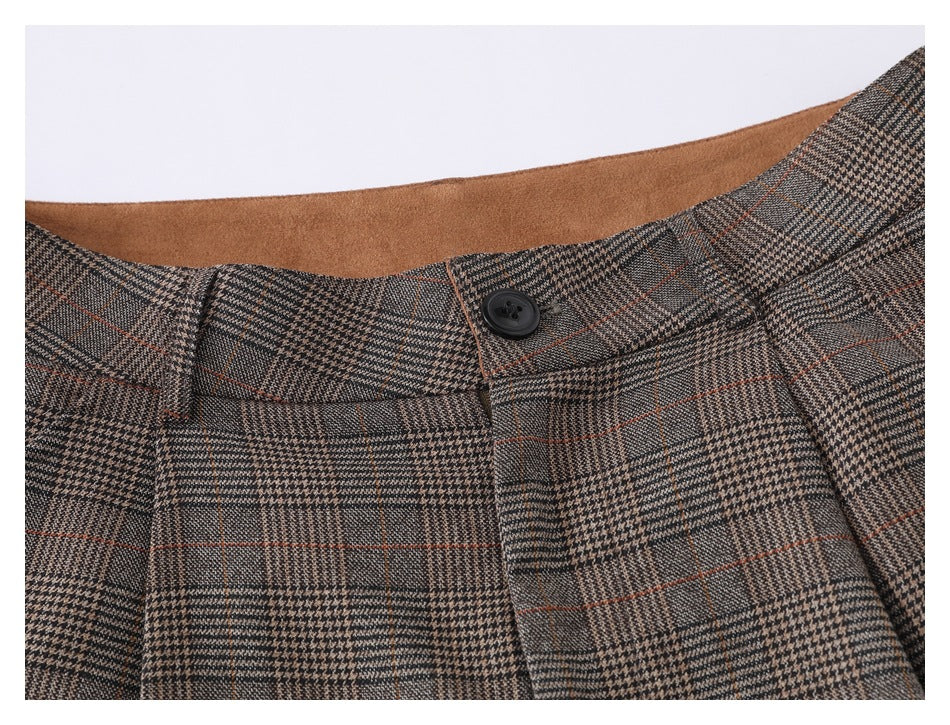 Close-up of brown-gray plaid trousers showing the waistband, belt loops, and a black button.
