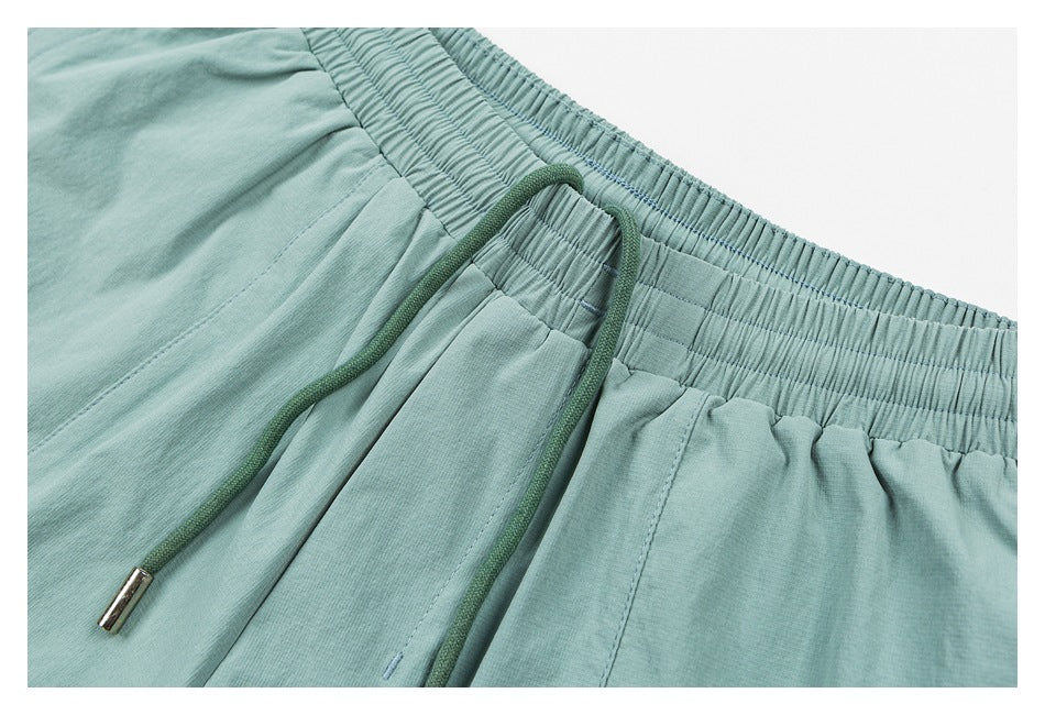 Close-up of mint-green shorts with a gathered waistband and green drawstring with a metal tip.