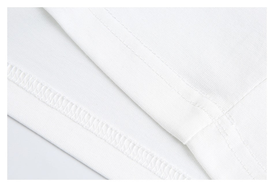 Close-up of white shirt fabric with folded hem and visible overlock stitching.