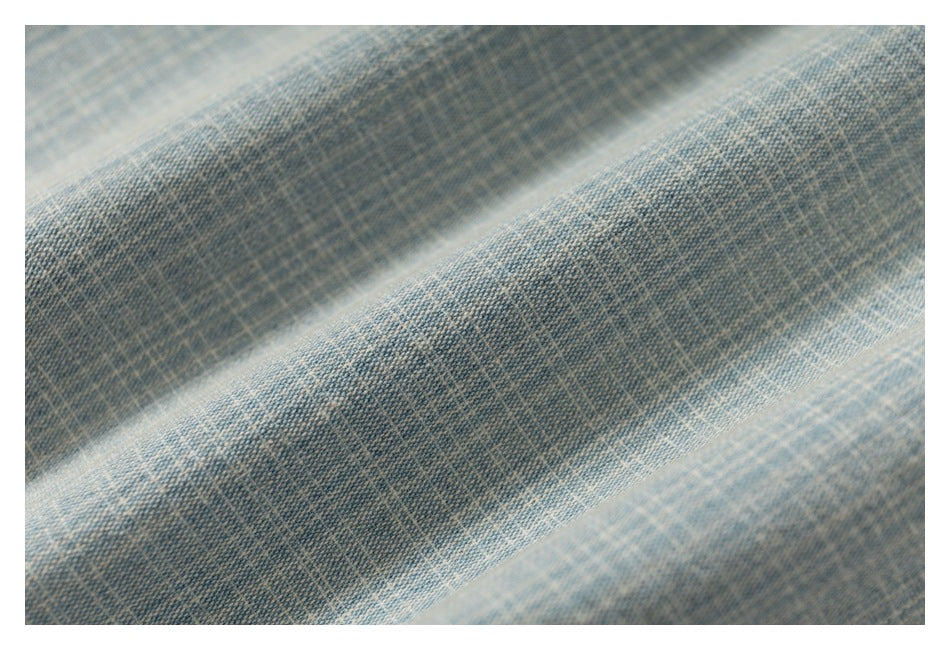 Extreme close-up of the light blue and cream woven shirt fabric, showing its textured pattern.