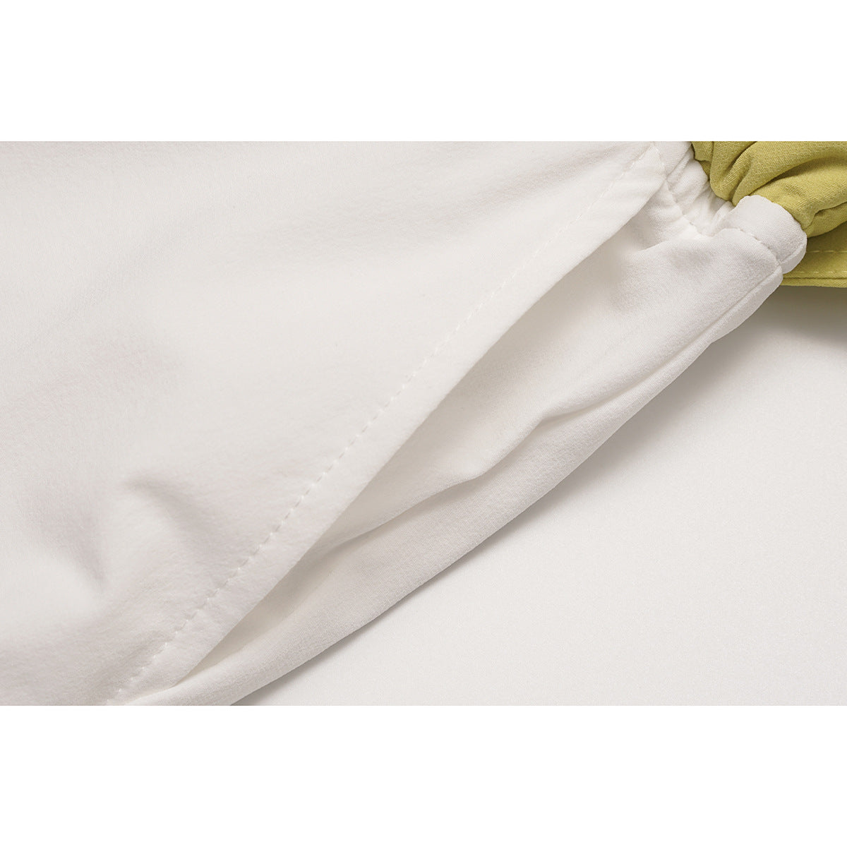 Close-up of white pants showing a stitched seam and folded fabric near the yellow waistband.