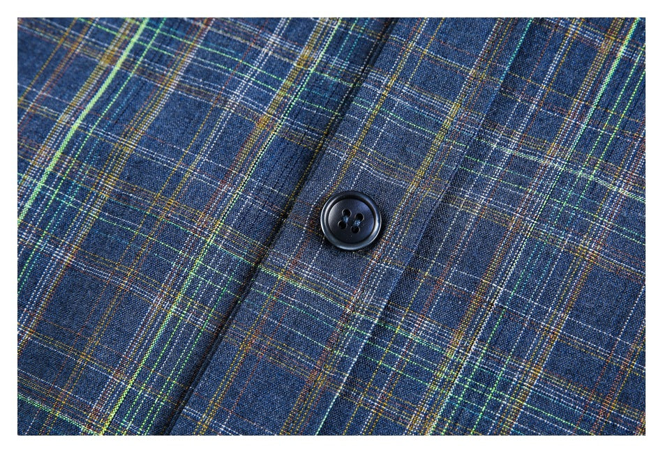 Close-up of a dark button on blue plaid shirt fabric with fine green, yellow, and white checks.