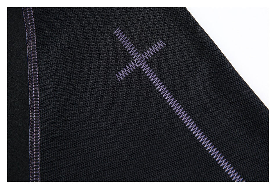 Close-up of black textured fabric with purple cross-shaped zigzag stitching and a vertical overlock seam.