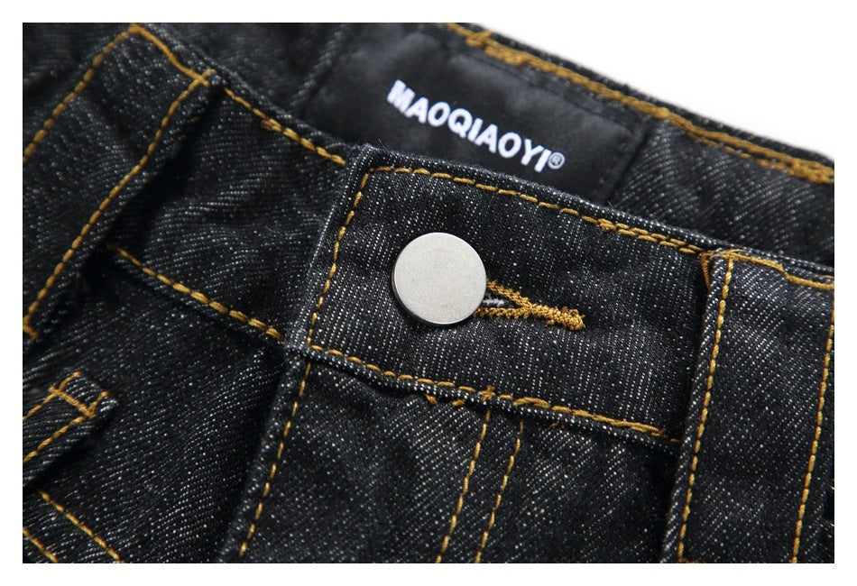 Close-up of a silver jeans button, black denim waistband, and sewn-in brand label.