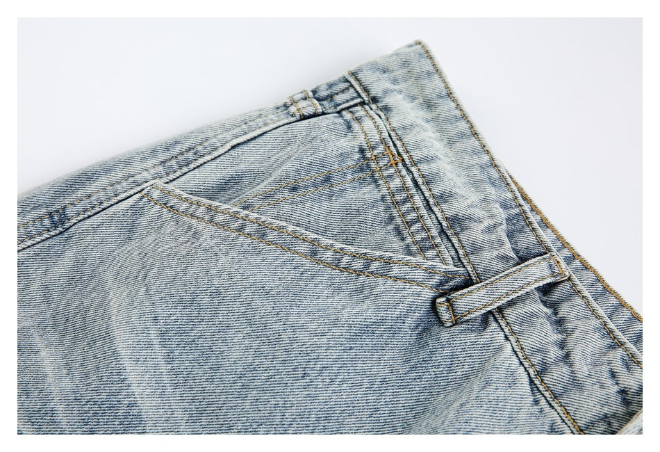 Close-up of the jeans' waistband, belt loop, pocket seams, and light-wash denim.