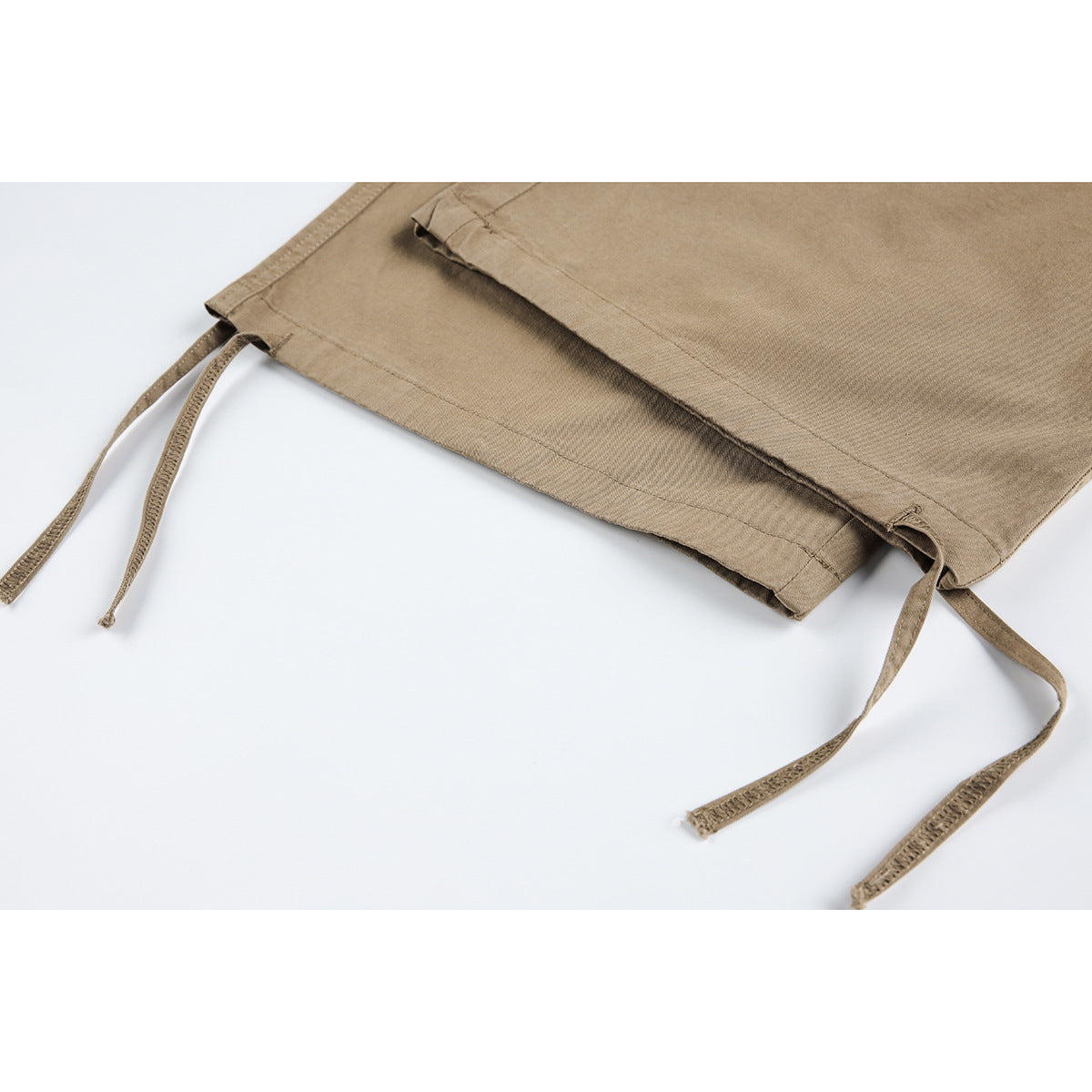 Close-up of tan pant hems with long adjustable drawstrings.