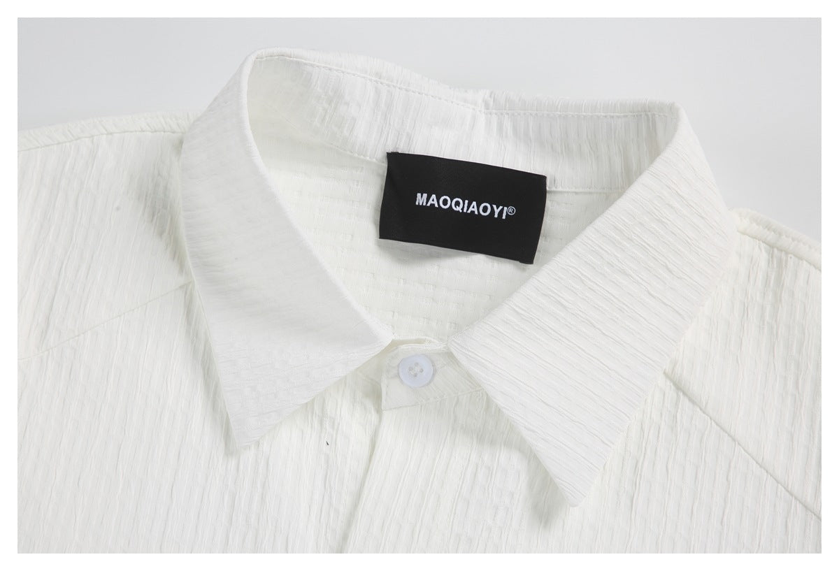 Close-up of a white textured shirt collar with a black sewn-in neck label and white button.