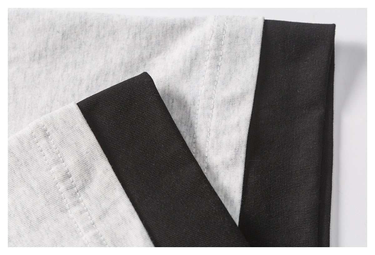 Close-up of light gray shirt seams and wide black ribbed trim.
