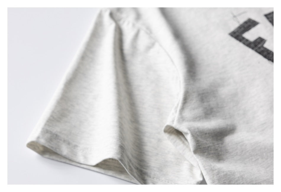 Close-up of a light heather-gray T-shirt sleeve and a cropped section of its black print.