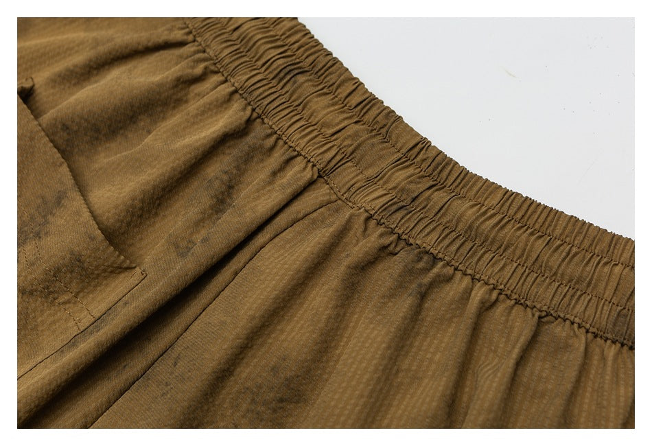 Close-up of brown shorts showing the gathered waistband and a stitched pocket.