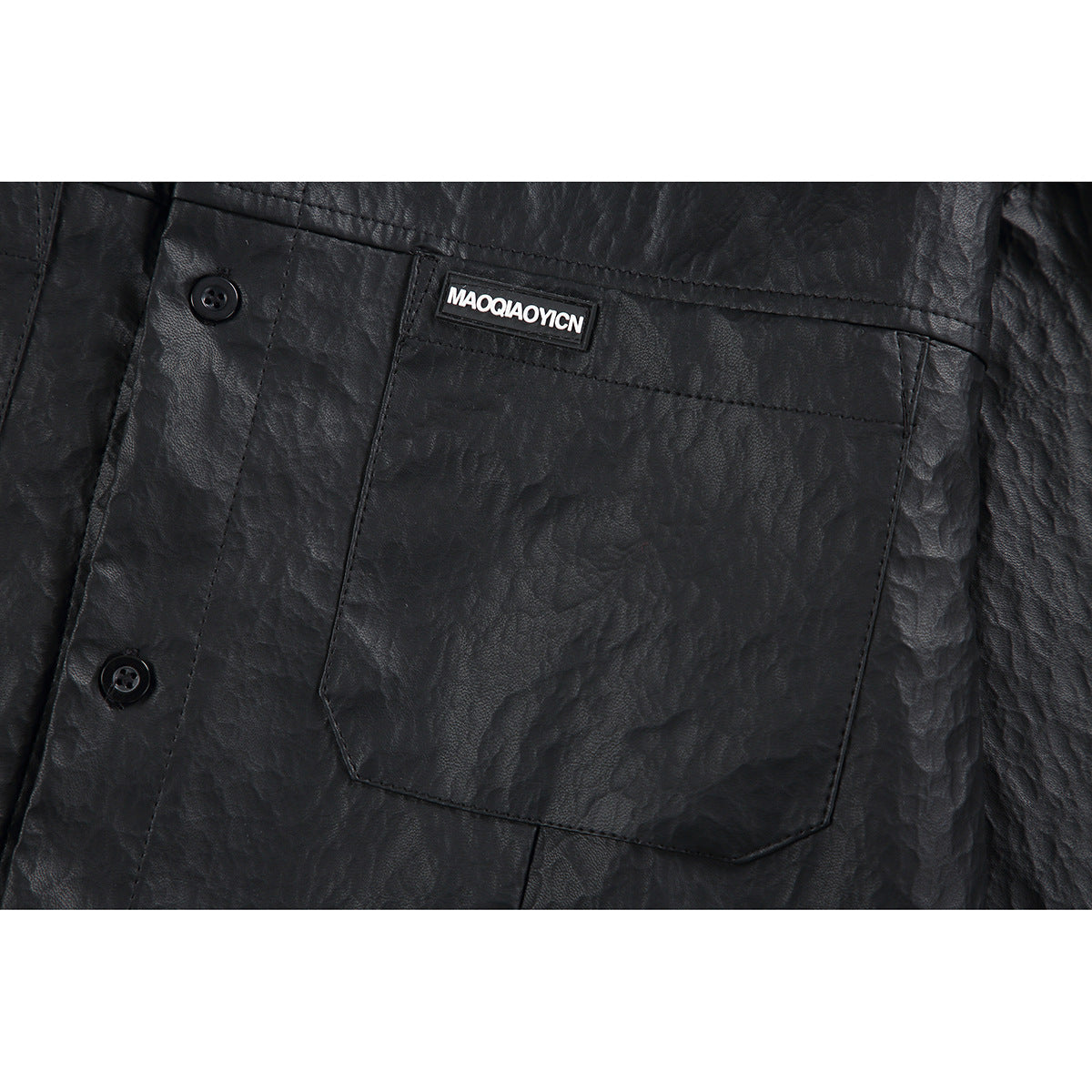 Close-up of the black shirt's chest pocket, buttons, crinkled surface, and sewn-on logo patch.