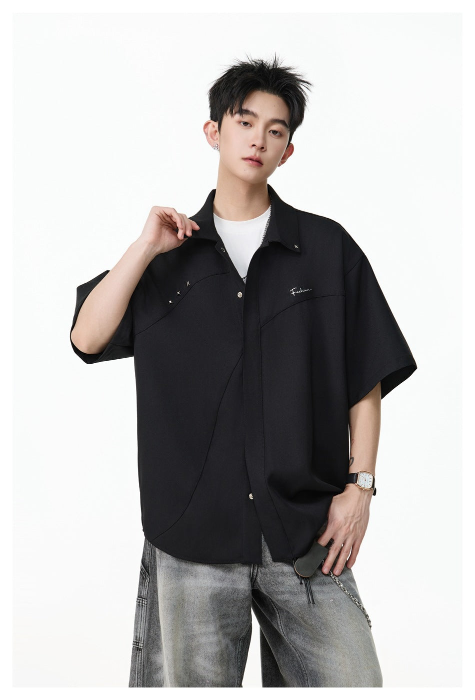 Model wearing the black short-sleeve relaxed shirt with snap placket, star studs and chest script embroidery, front view