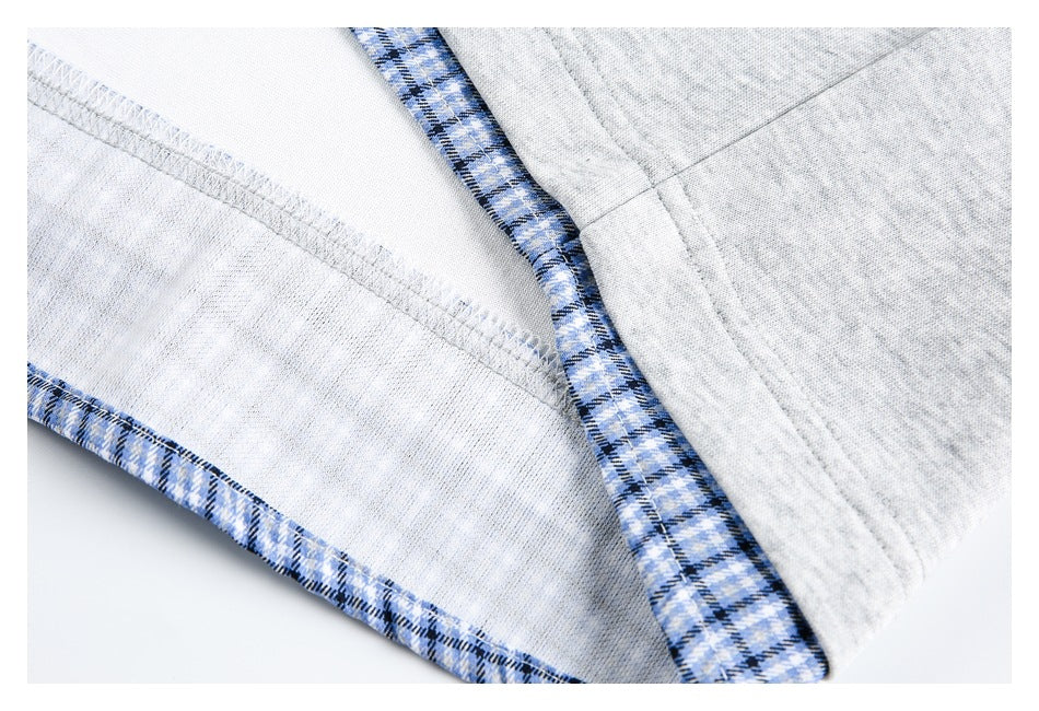 Inside view of the light gray shirt showing overlocked stitching and blue plaid trim.