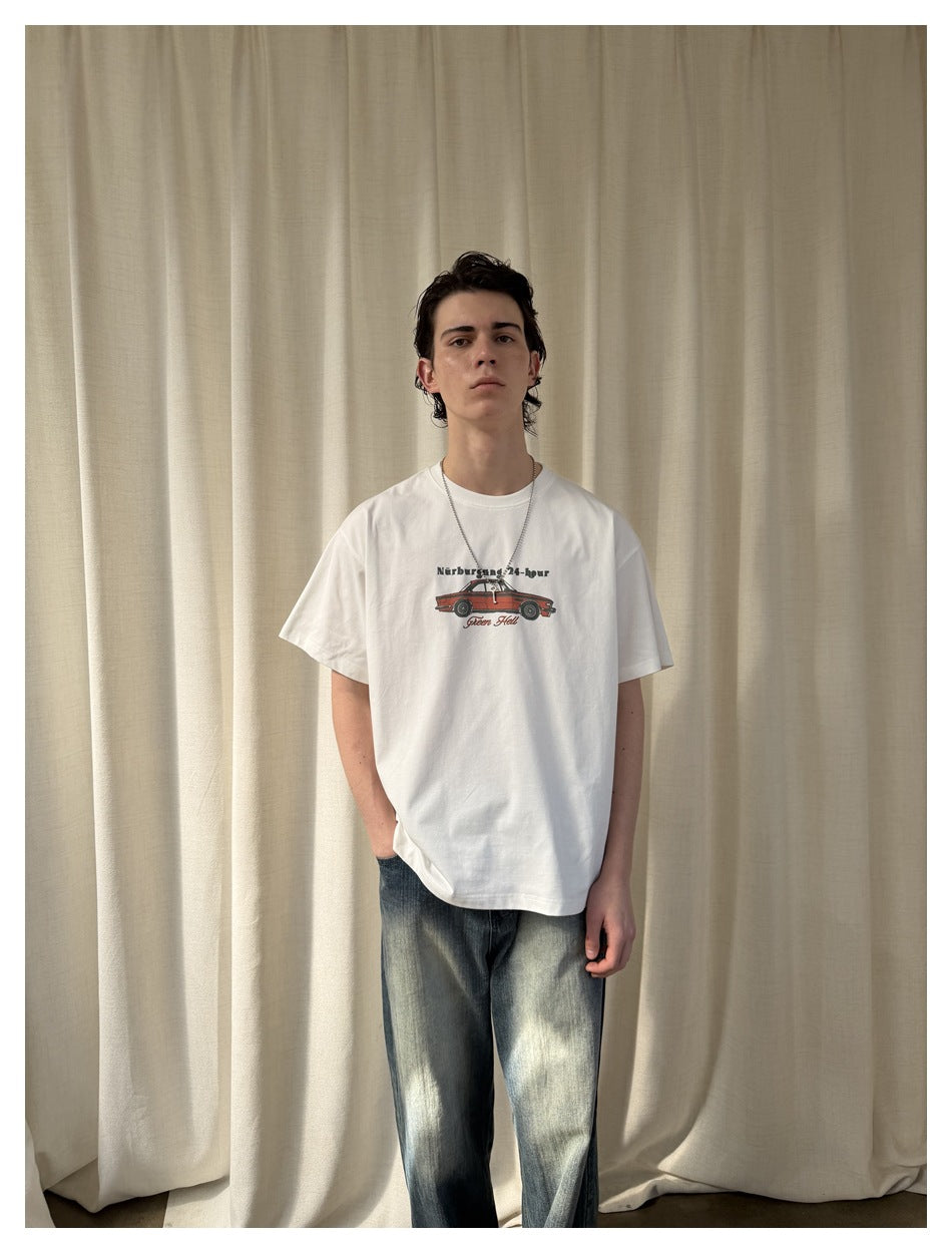 Closer front view of a model wearing a white T-shirt with a small red car graphic and loose faded jeans.