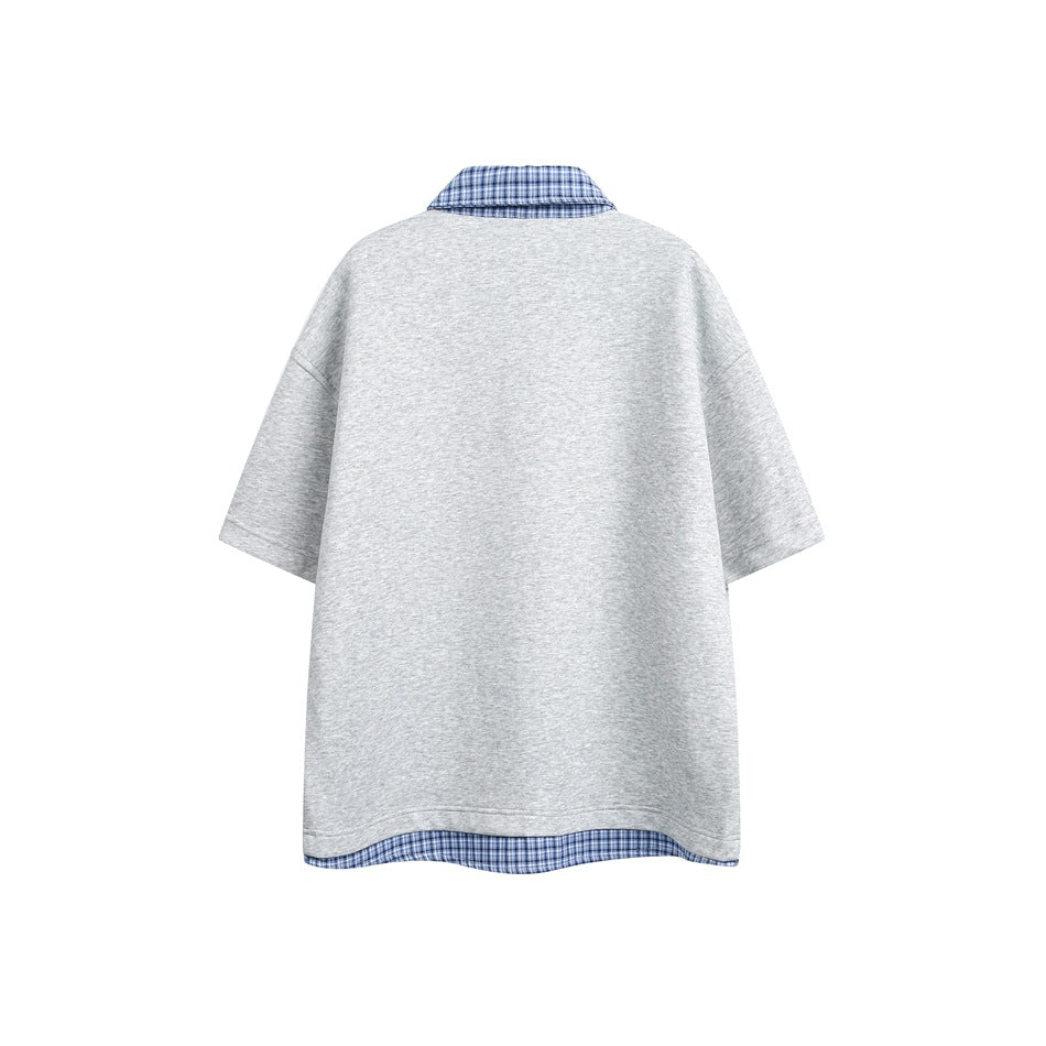 Back view of a light gray short-sleeve top with a blue plaid collar and matching plaid hem trim.
