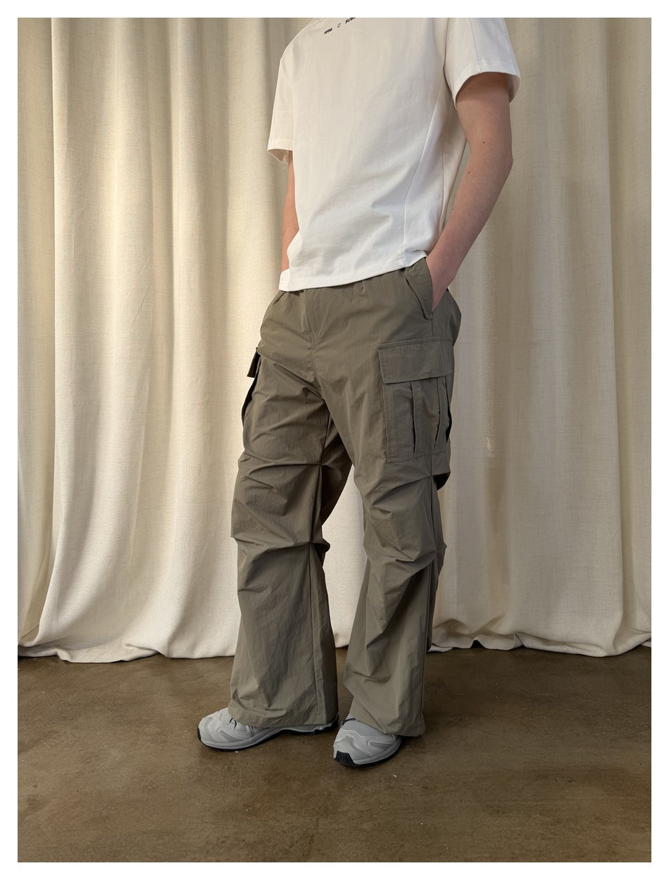 Person wearing army green cargo pants with a white tee and gray sneakers, side view, hands in pockets
