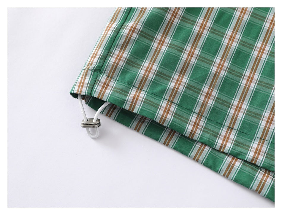 Close-up of the green plaid shirt hem with an adjustable drawcord and toggle.