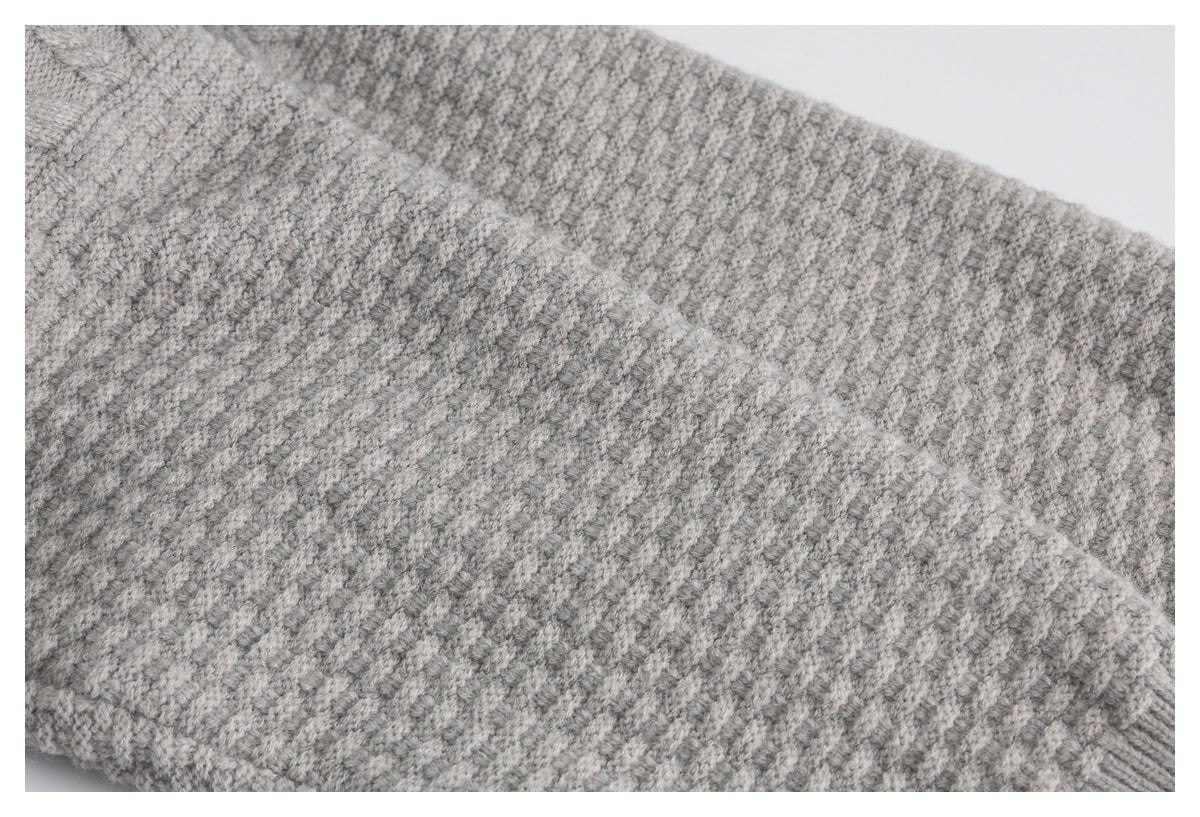 Close-up of a light gray marled knit garment showing its textured stitch pattern.