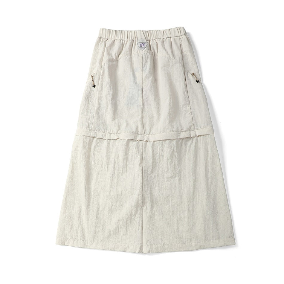 Back view of an off-white long skirt with an elastic waistband, side zip pockets, and a small label at the waist.