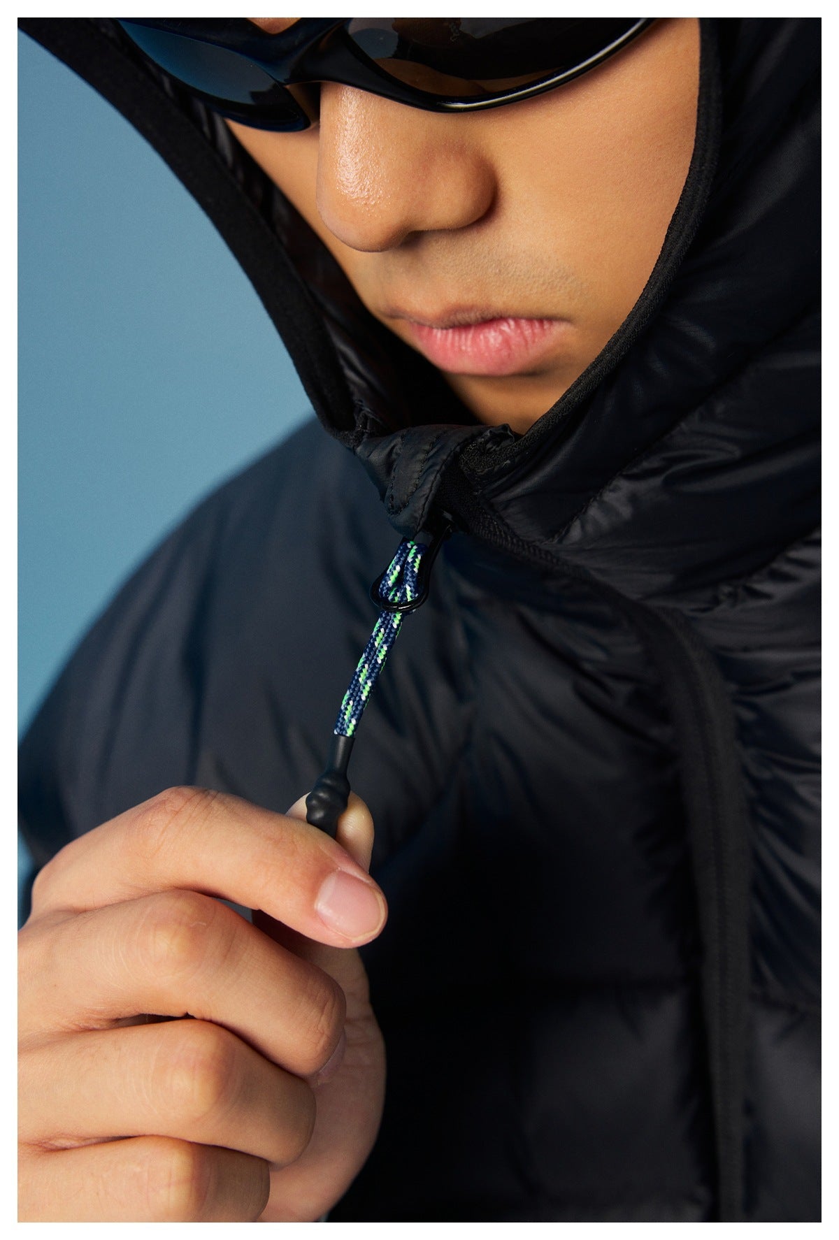 Close-up of a black puffer jacket's raised collar and multicolored drawcord toggle.