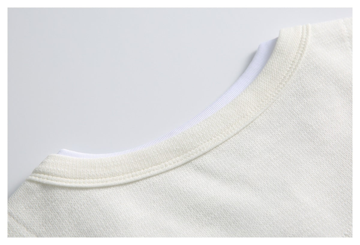 Close-up of the ivory knit top's rounded neckline and narrow white inner trim.