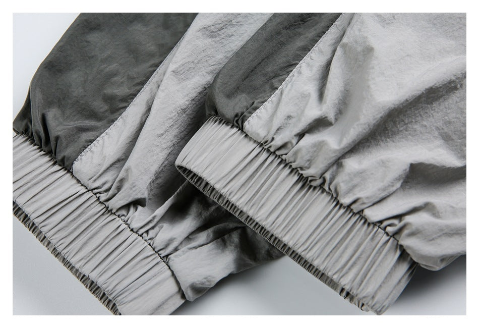 Close-up of a light gray garment with dark gray panels and gathered elastic bands at the edges.