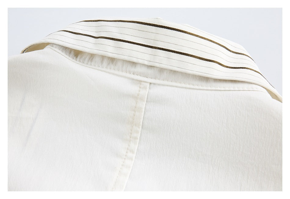 Close-up of the back collar of an ivory garment, lined with narrow brown stripes.