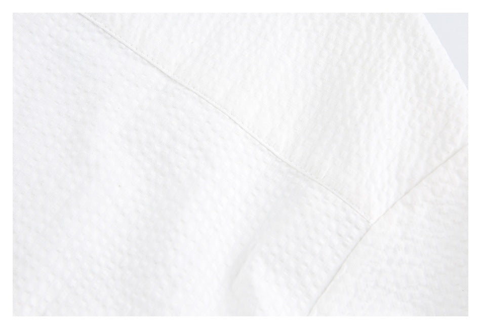 Close-up of a diagonal seam across the white textured shirt fabric.
