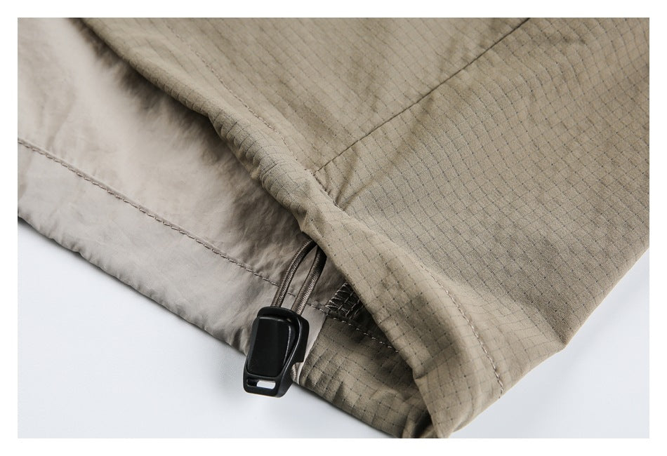 Close-up of the beige jacket hem with a black cord-adjustment toggle.