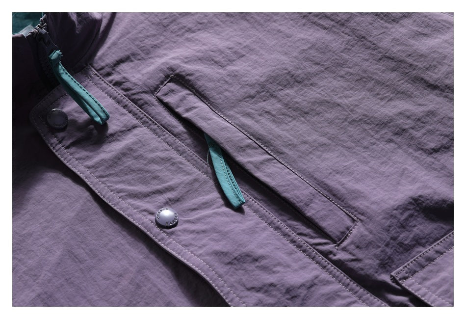 Close-up of the purple jacket front with snap-button placket, turquoise zipper pulls, and a vertical pocket.