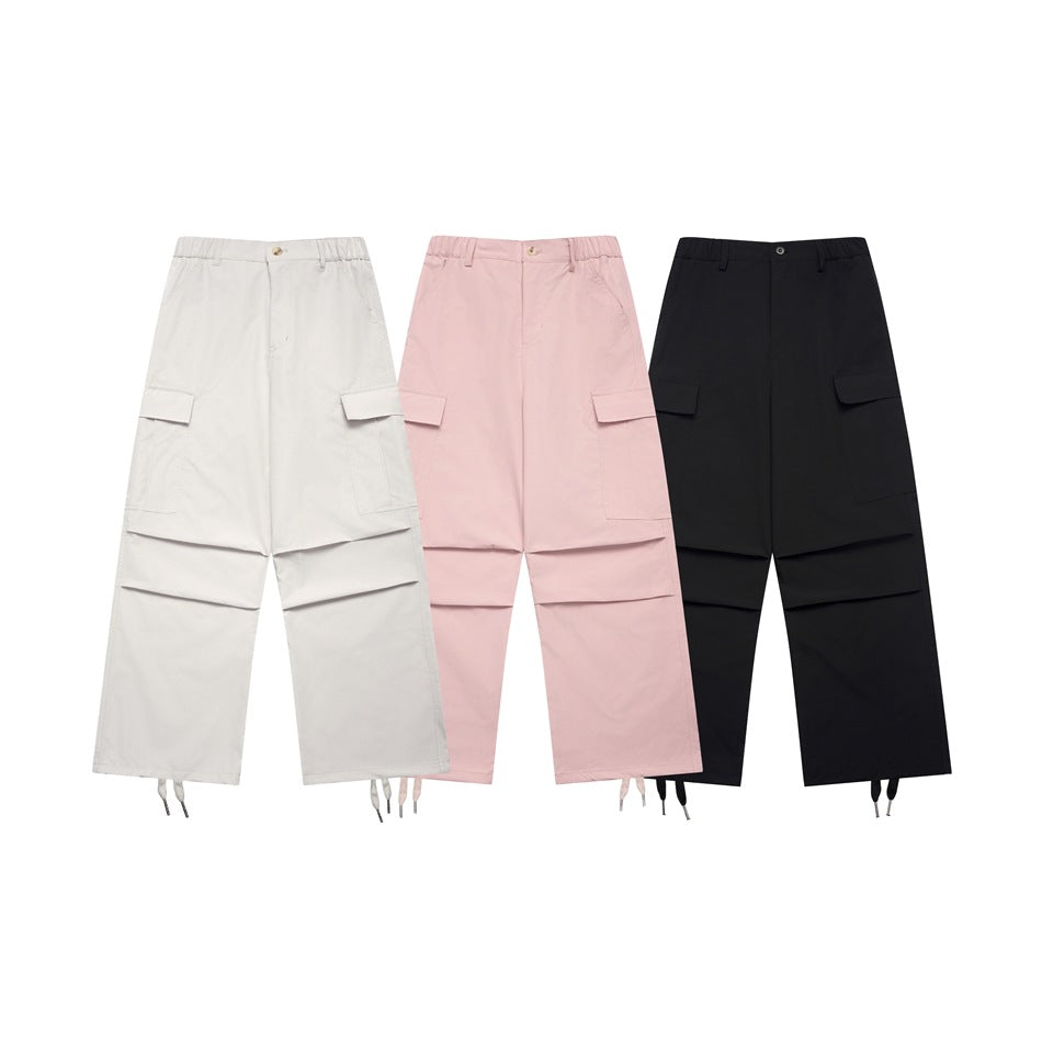 Front views of wide-leg cargo pants in light gray, pale pink, and black, with flap pockets and drawstring hems.