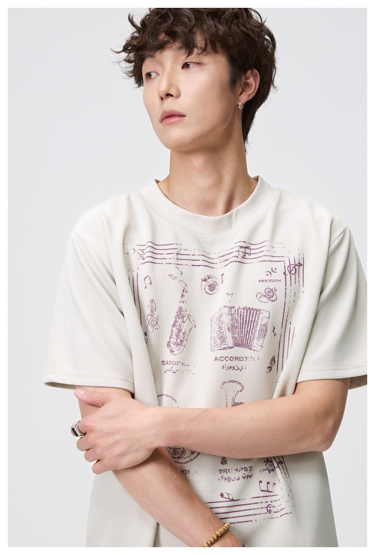Close view of a model wearing an ivory T-shirt with a burgundy musical-instrument graphic.