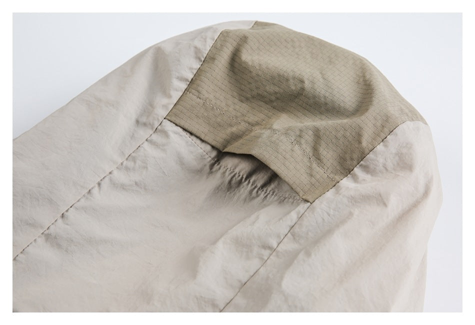 Close-up of a beige garment seam joining a textured tan panel to softly gathered fabric.