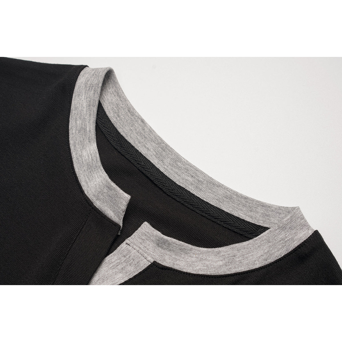Close-up of a black top with a contrasting heather-gray crew neckline and inner neck binding.