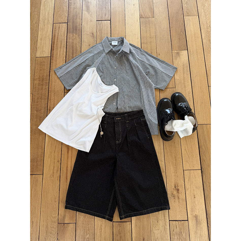 Flat lay of a gray striped shirt, white tank, black shorts, black shoes, and white socks.