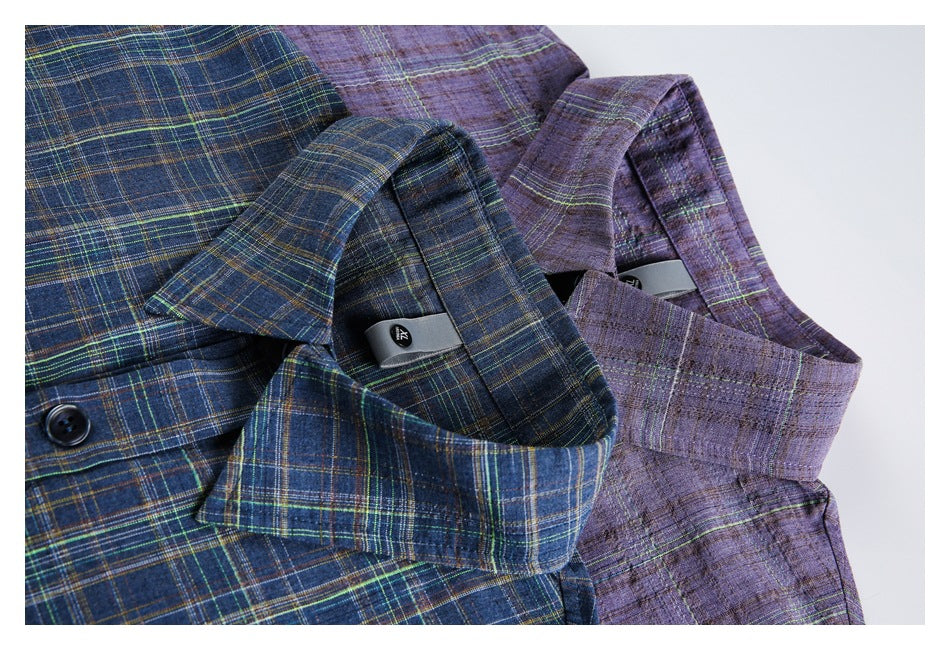Close-up of blue and purple plaid shirts showing their collars, button fronts and small inner labels.
