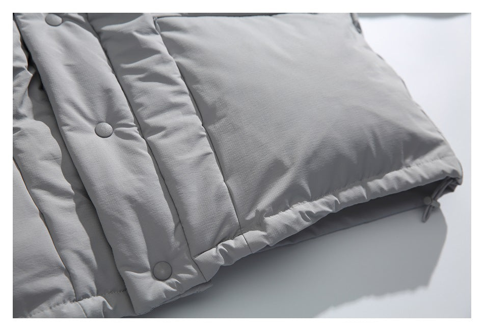 Close-up of the lower front and hem of a light gray padded jacket with snap buttons.