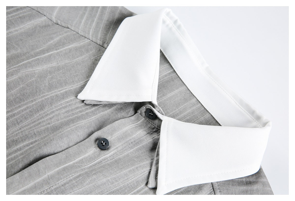 Close-up of a gray shirt with a wide white collar and dark buttons.