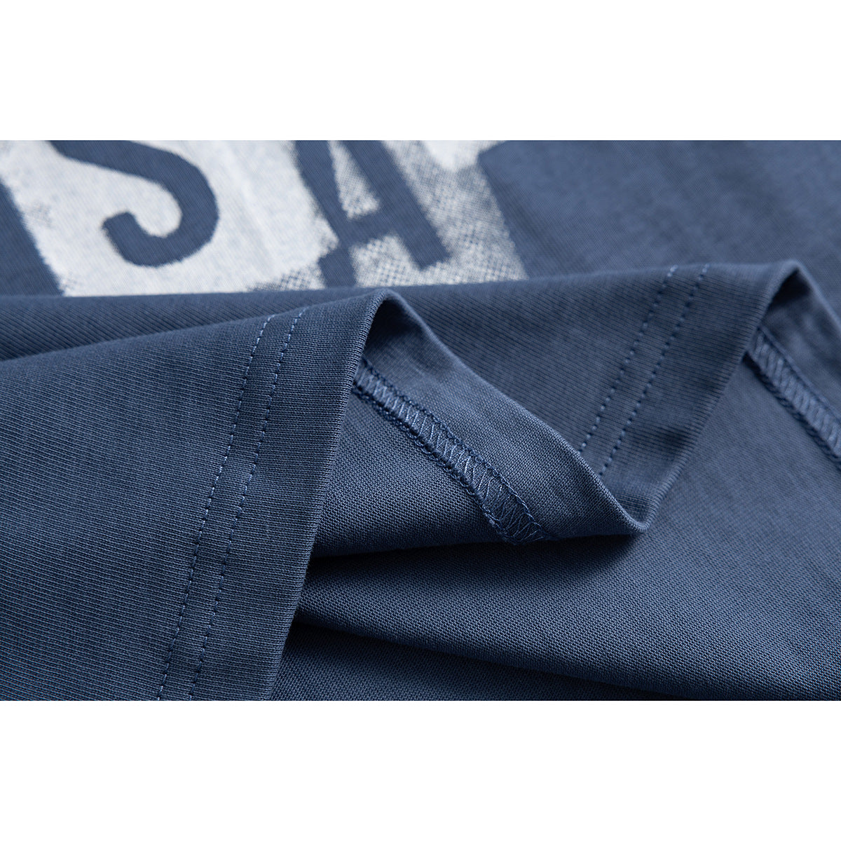 Close-up of the slate-blue T-shirt's ribbed sleeve cuff and overlocked seams.