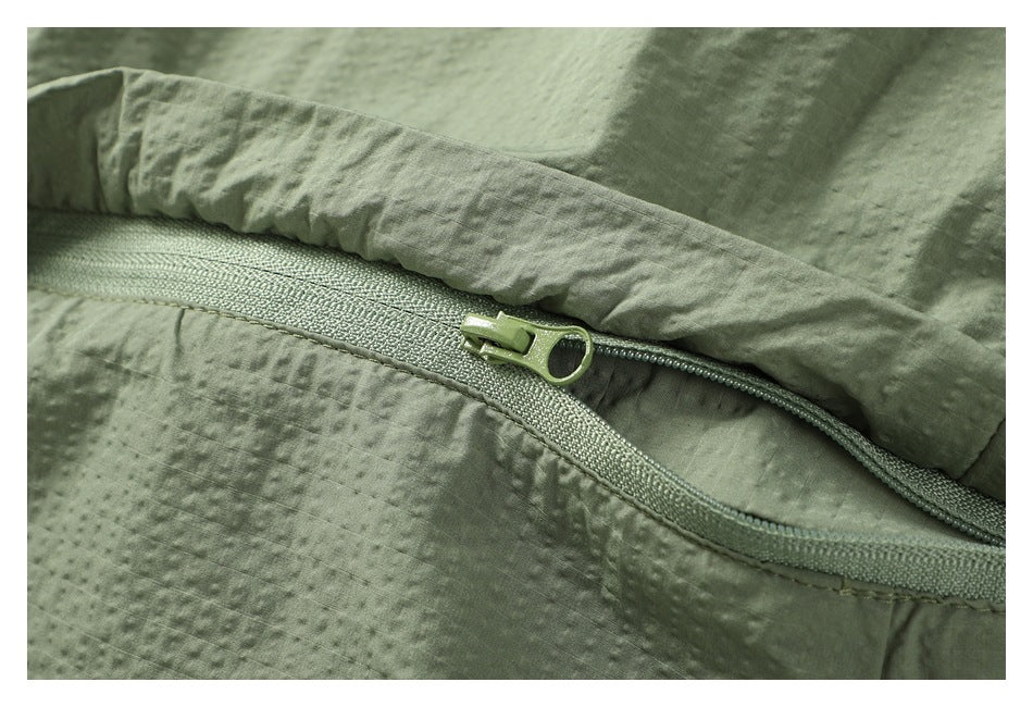 Close-up of a zipper and seam on sage green textured fabric.