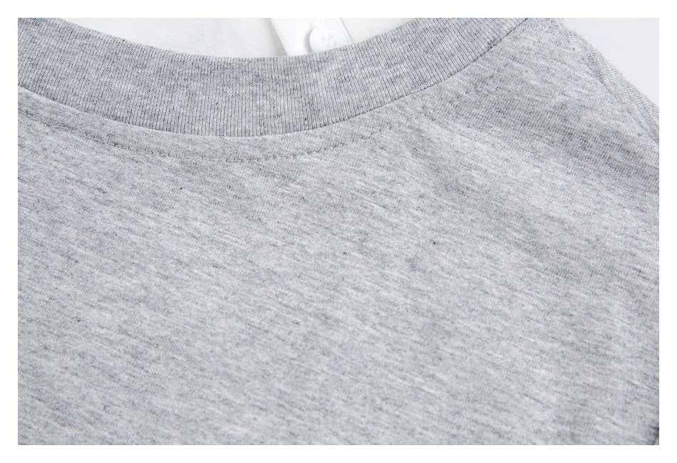 Close-up of a heather-gray knit shirt’s ribbed crew neckline, with a white buttoned garment visible behind it.