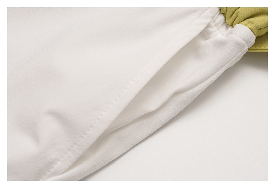 Close-up of a white pant leg seam and hem drawcord beside the pale yellow-green waistband ruffle.