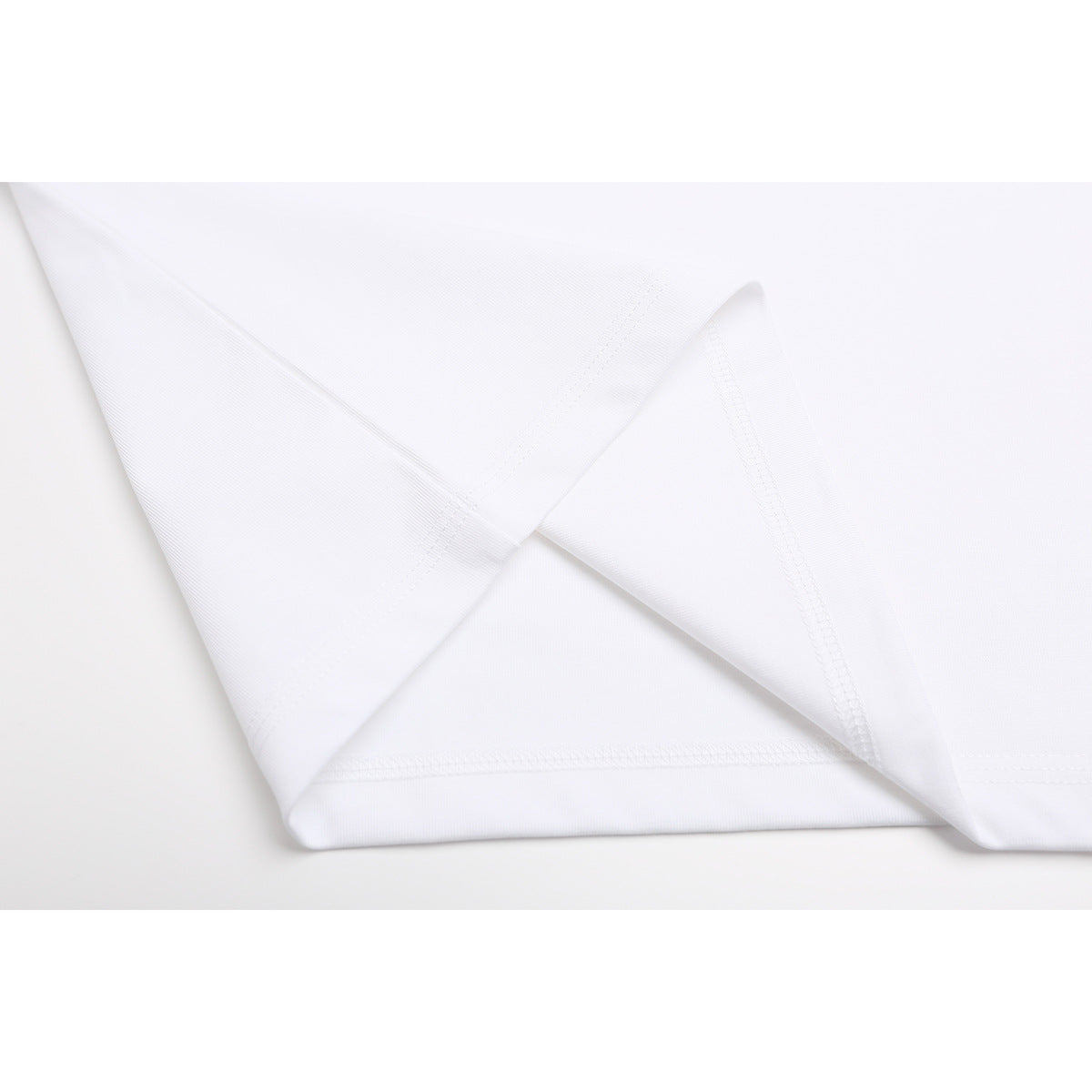 Close-up of a white T-shirt's folded bottom hem and stitching.
