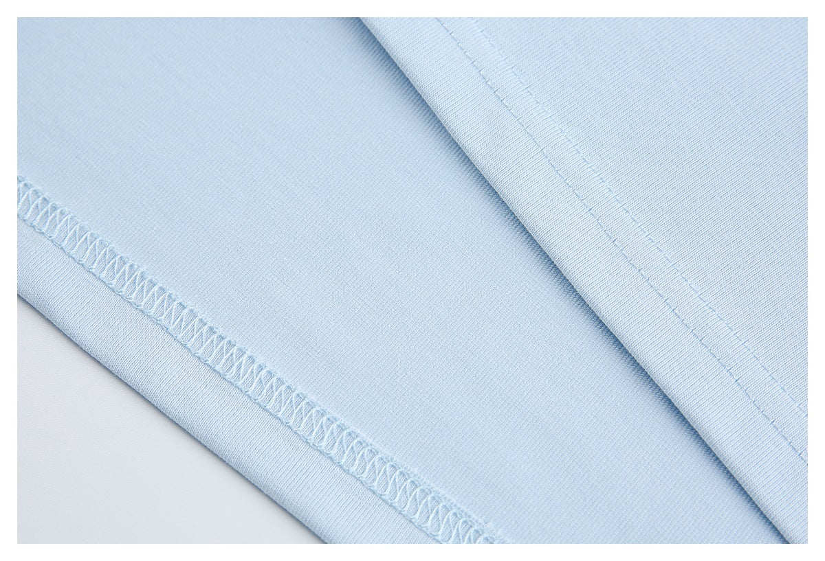Close-up of light blue garment fabric showing an overlocked seam and parallel stitching.