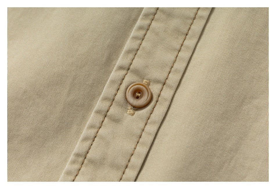 Close-up of a tan garment's stitched placket with a round brown button.