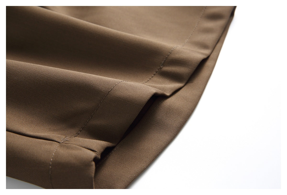 Close-up of the brown trousers' stitched hem and folded fabric edge.