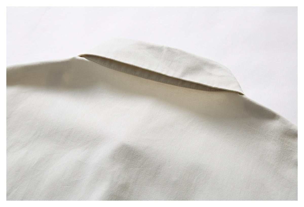 Close-up of the folded collar and upper back of an ivory shirt.