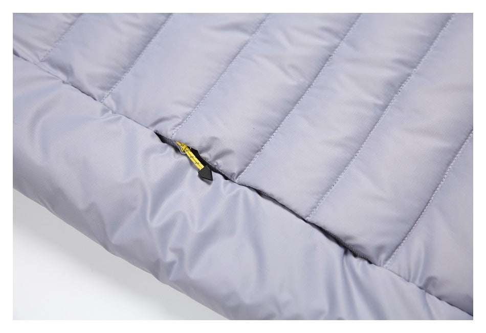 Close-up of quilted light gray-lavender vest fabric and a yellow pocket zipper pull.