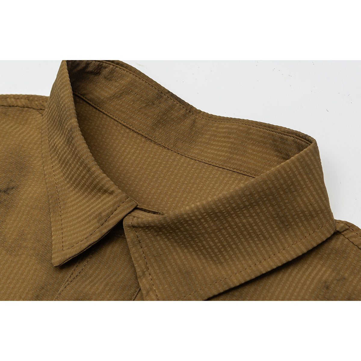 Close-up of a brown textured shirt collar with visible stitching and a subtle woven pattern.