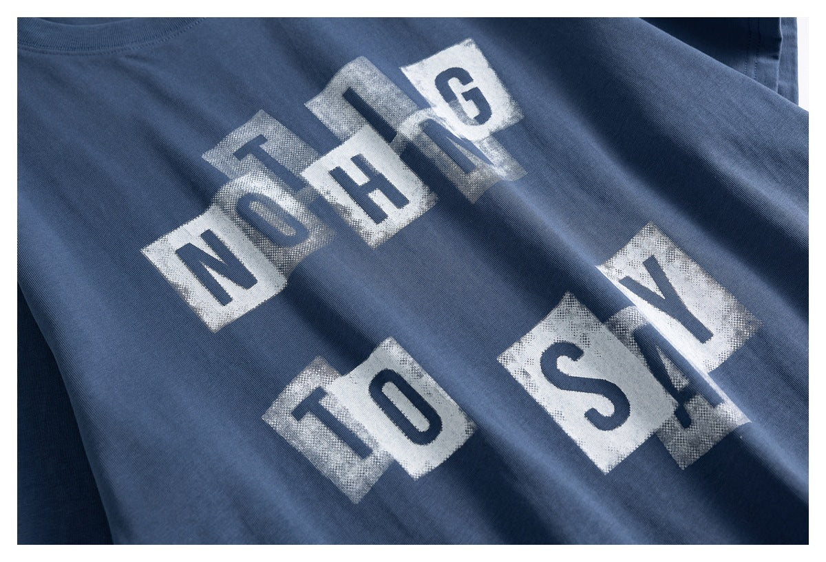 Close-up of distressed white block lettering printed across the slate-blue T-shirt.